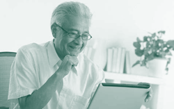 A picture of an elderly person in front of a laptop computer.