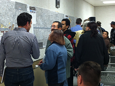 Small groups of people at a public meeting talking among themselves and looking at maps with information about the Bernalillo Boulevard corridor.