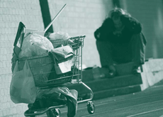 A picture of a chronically homeless person with belongings in grocery cart.