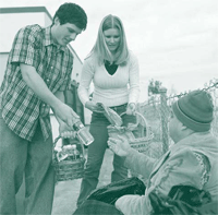 A picture of two young people helping a homeless man.