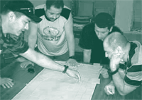 A picture of three workers studying a value stream map that will improve the flow of materials along the production line in factory-built housing.