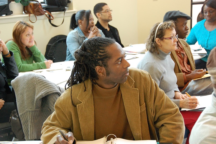 Photograph of nine students seated at tables in a meeting room and taking notes during a Community Business Academy course.