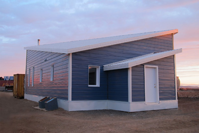 Photograph of the front and side facades of the one-story Buckland prototype home, displaying the roof ridge that runs diagonally from corner to corner.