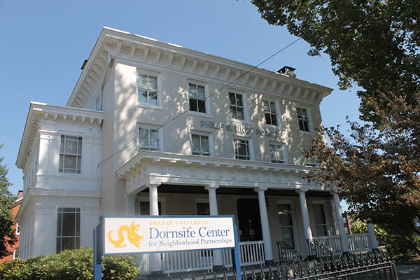 Photograph of front façade of the Philip B. Lindy House, a nineteenth century three-story residential building behind an identification sign, “Drexel University Dornsife Center for Neighborhood Partnerships.”