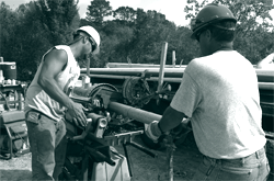 A picture of workers cutting a length of pipe for a sewage line.