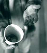 A picture of a homeless man holding a cup for coins.