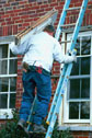 Construction worker on ladder carrying window 
