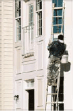 Man on ladder painting exterior windows 
