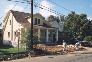 Older house with workers walking in front