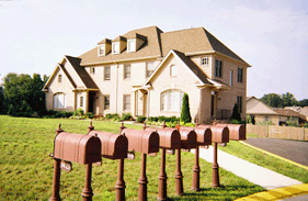 Photograph of beige brick quadraplex with eight mailboxes in front.