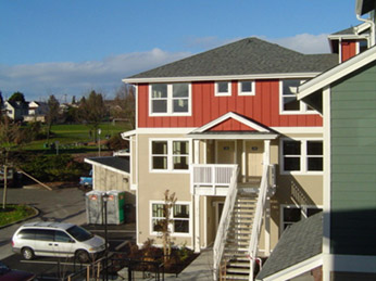 Photograph of three-storey apartment building with red and beige siding.