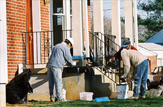 Three workers finishing front porch of new house.