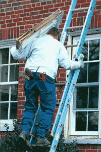 Man carrying a window up a ladder.