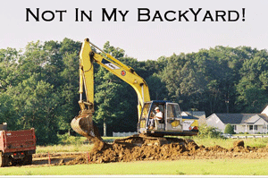 A photograph of an excavator in a residential neighborhood.
