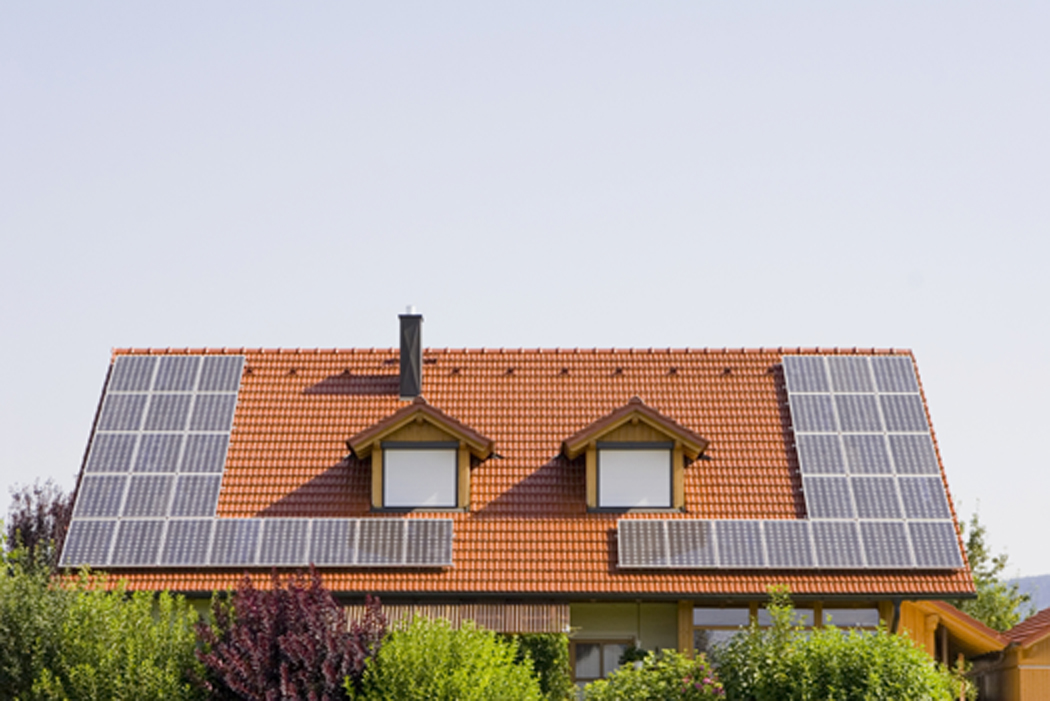 A view of solar panels on the roof of a residential building.