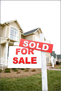 A picture showing a forsale/sold sign in front of a home.