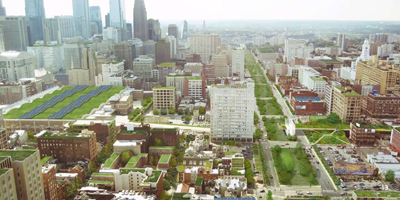 Low-angle aerial photograph looking west up the Vine Street Expressway, with a portion of Center City visible. Photographic enhancements show green roof tops and plantings within public rights-of-way.